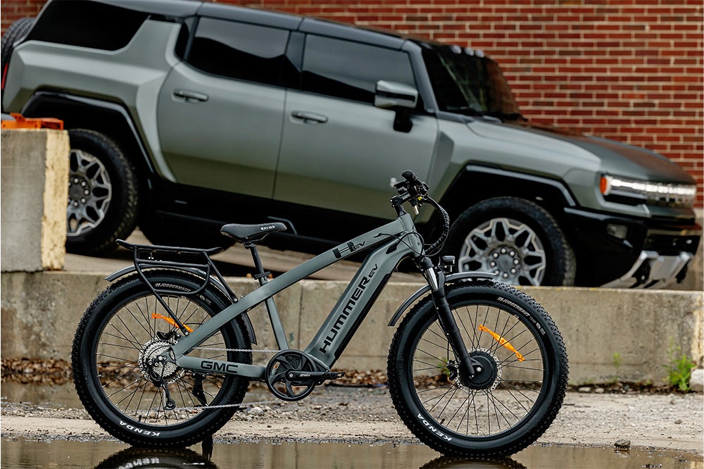 The AWD Electric Bike and Hummer EV are parked side by side in front of an old building.